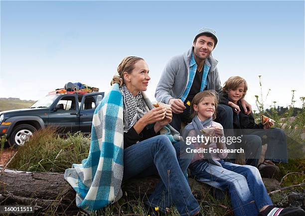 family eating sandwiches - front view portrait of four children sitting on rock stock-fotos und bilder