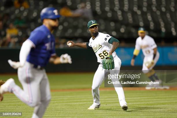 Pitcher Dany Jimenez of the Oakland Athletics fields the ball and throws to first base to get the out of Ezequiel Duran of the Texas Rangers in the...