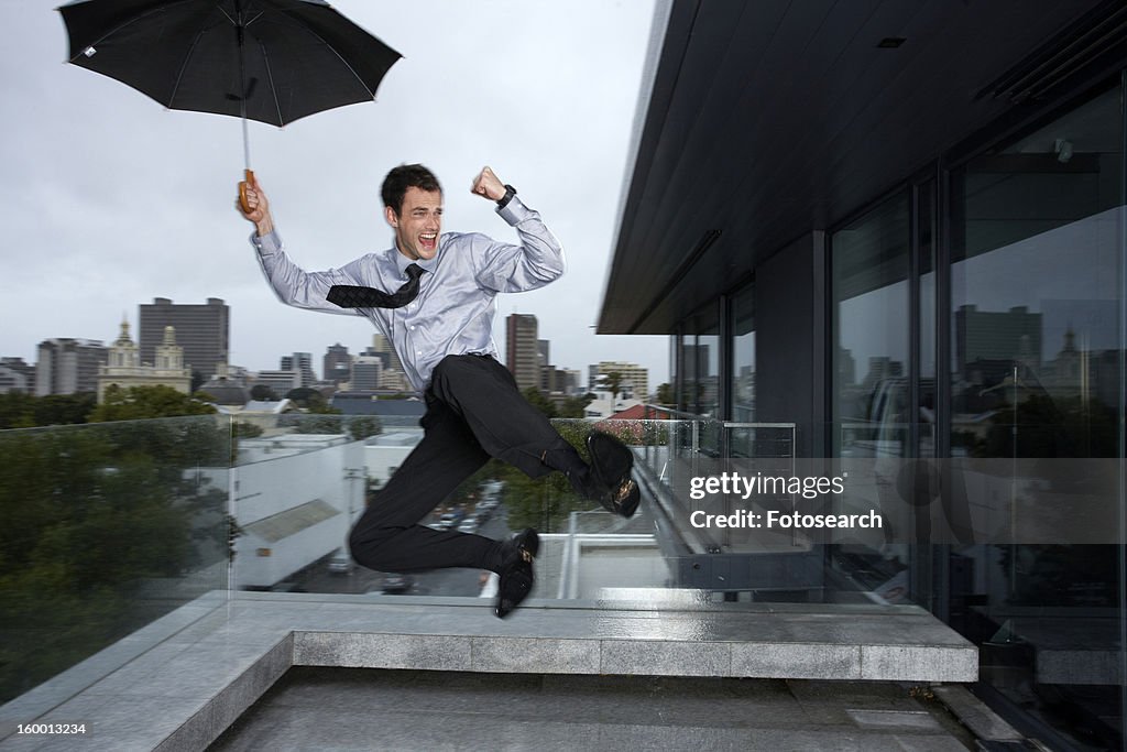 Businessman jumping in the rain