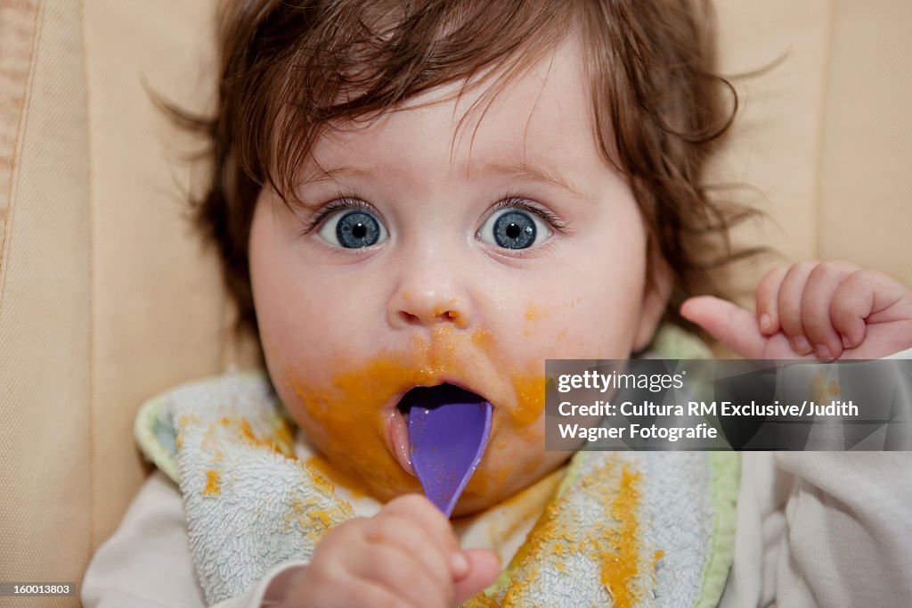 Surprised baby eating messy food