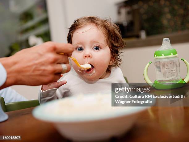 parent feeding baby girl at table - femme bras tendu cuillère photos et images de collection