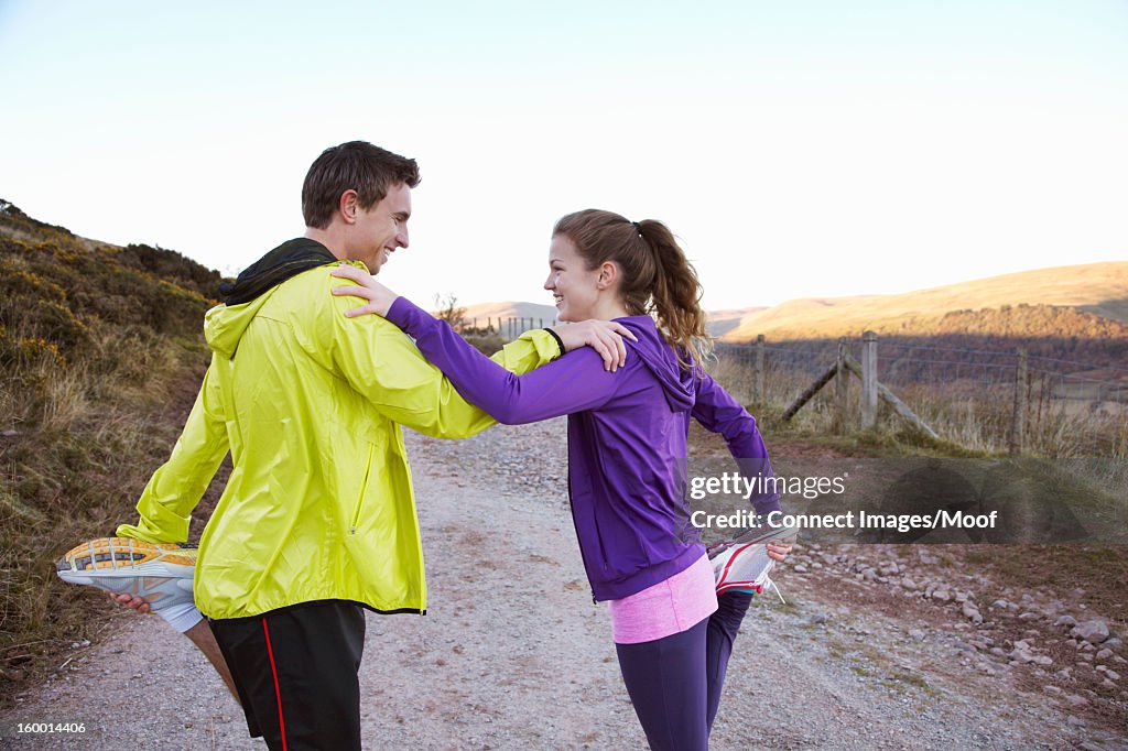 Couple stretching together on dirt road