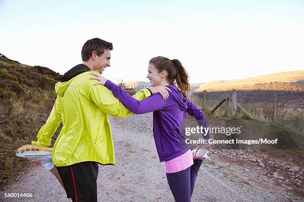 Couple Stretching Together On Dirt Road, Bildbanksbilder