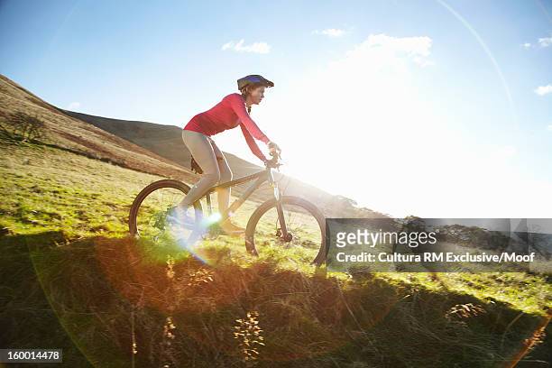 woman riding bicycle in grassy field - welsh hills stock pictures, royalty-free photos & images