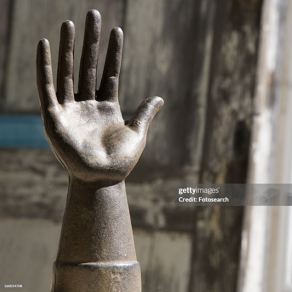 Metal statue of hand against wooden background.
