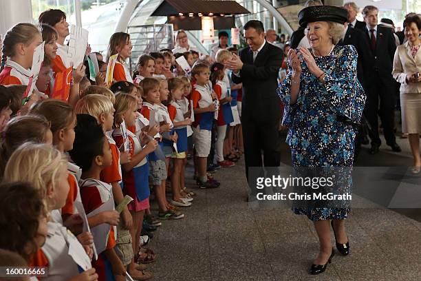 Queen Beatrix of the Netherlands sings along with dutch students from the Hollandse School after touring the Singapore A*Star Fusionworld on January...