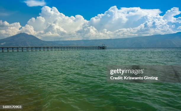 the bridge pumps fresh water from lake toba to the people's house, with mount pusuk buhit as the background. - samosir island stock pictures, royalty-free photos & images
