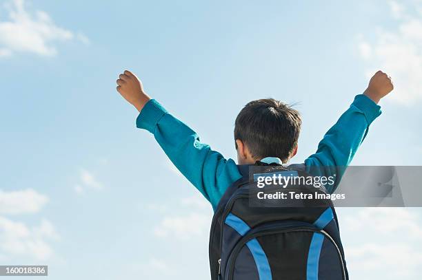 boy (6-7) wearing backpack punching air - beginn des schuljahres stock-fotos und bilder