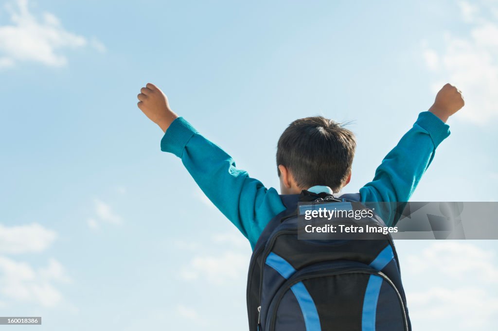 Boy (6-7) wearing backpack punching air