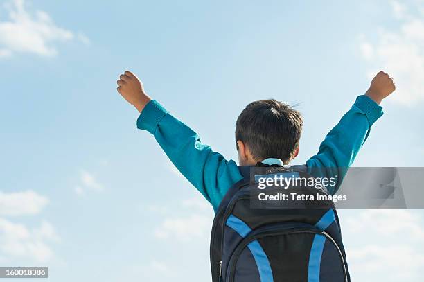 boy (6-7) wearing backpack punching air - back to school - fotografias e filmes do acervo