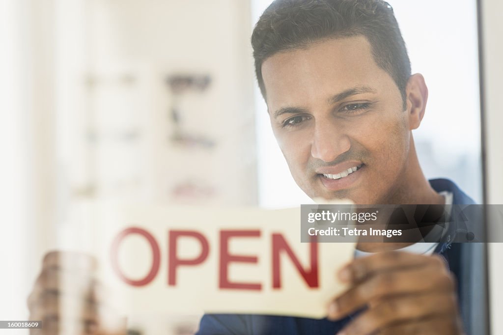 Man placing open sign on door