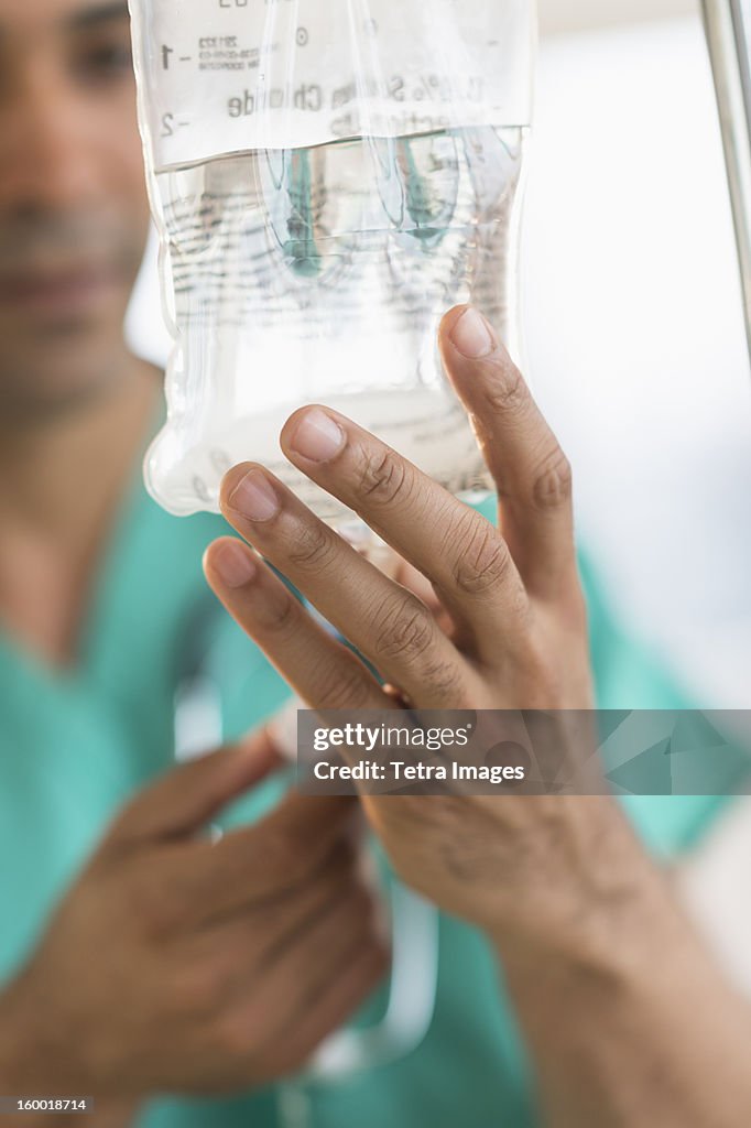 Male surgeon attaching iv drip on hospital