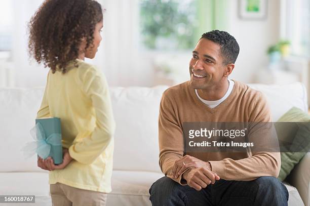 daughter (6-7) hiding gift for her father behind her back - child giving gift stock pictures, royalty-free photos & images