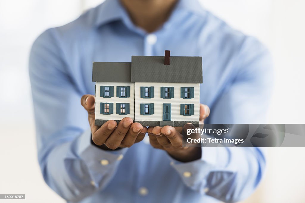 Man's hands holding model home