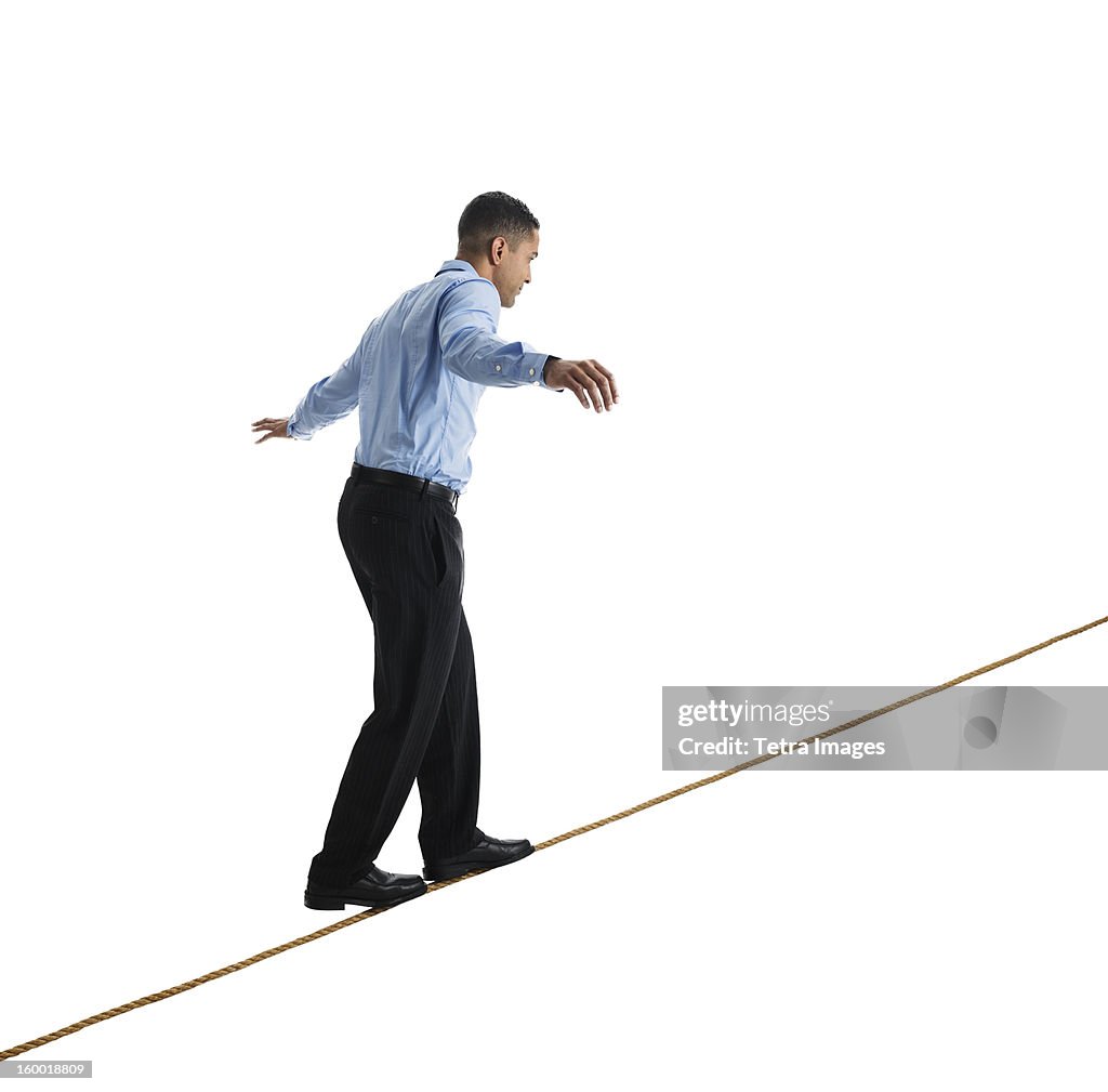Man balancing on tightrope, studio shot