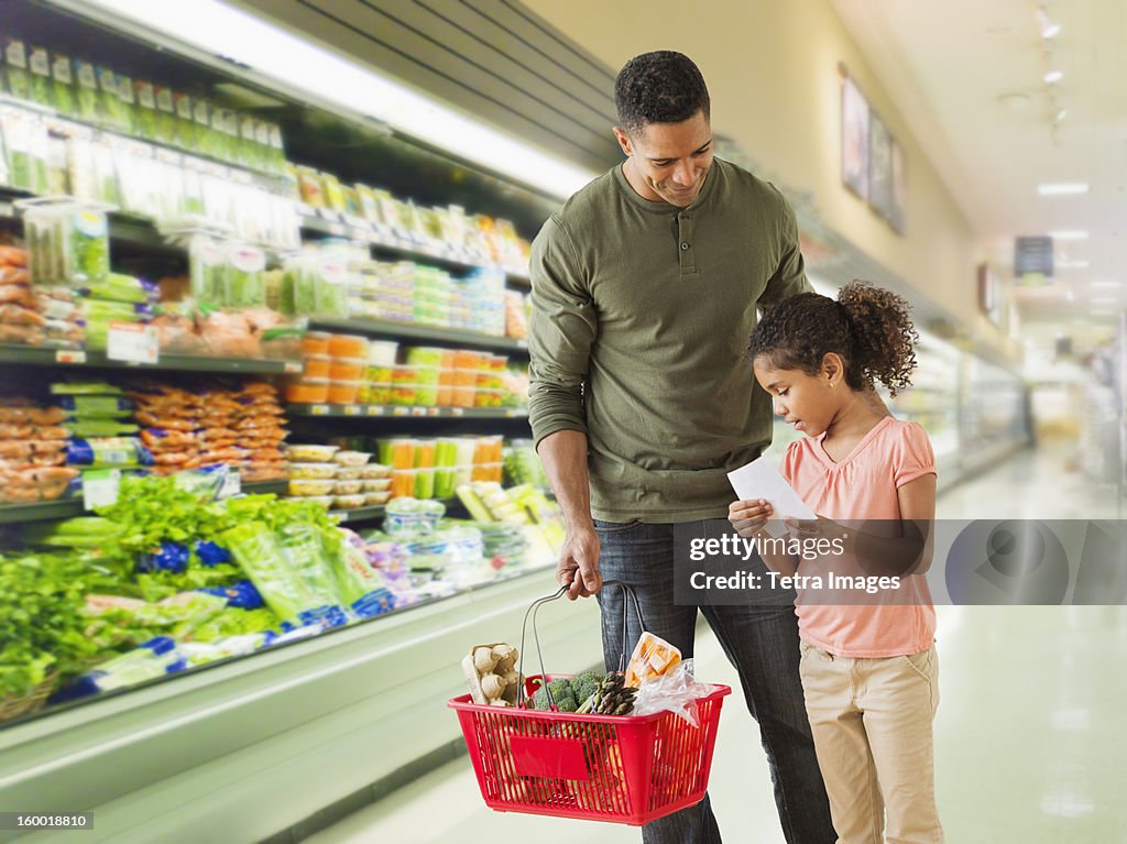 Father with daughter (6-7) shopping in supermarket
