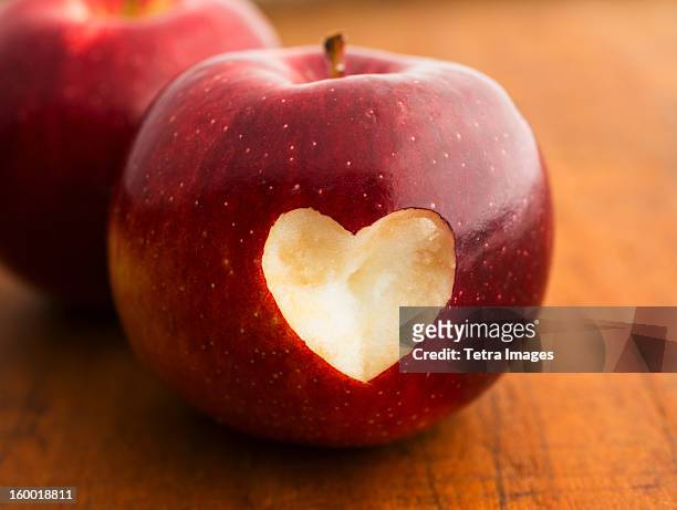 close up of apple with missing bite in heart shape, studio shot - apple heart stock pictures, royalty-free photos & images