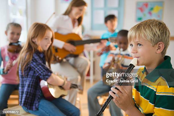 school children (8-9) with teacher playing instruments during music class - kids instruments stock pictures, royalty-free photos & images