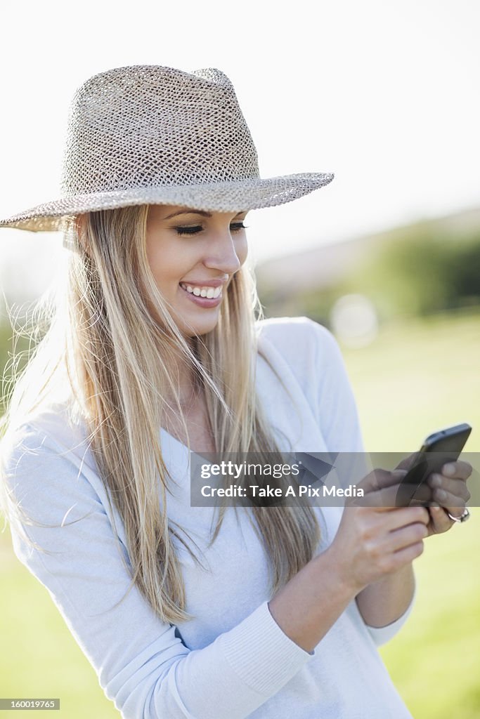 Portrait of smiling woman in straw hat using mobile phone