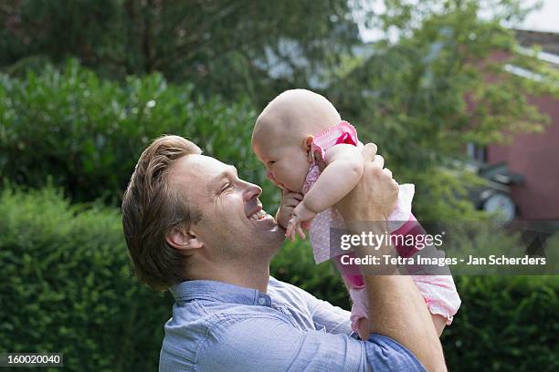 netherlands, mijnsheerenland, father holding baby daughter (6-11 months) in park - mijnsheerenland stock pictures, royalty-free photos & images