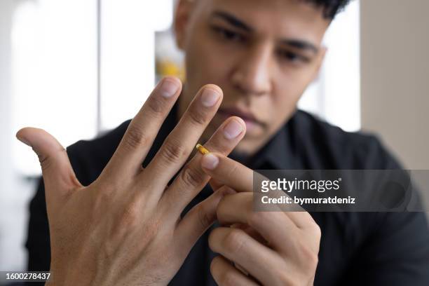 hands of male who is about to taking off his wedding ring. divorce concept - taking off wedding ring stock pictures, royalty-free photos & images