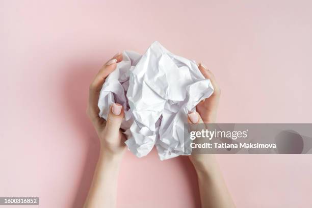 crumpled white paper in female hands on a pink background top view. concept of creativity and failed idea. - paper wrinkled stock pictures, royalty-free photos & images