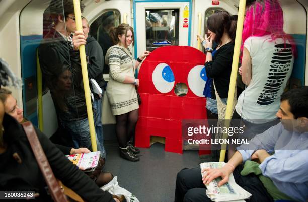 Two girls stand next to a cardboard of a Pac-man ghost on the London underground after leaving the "MCM London Comic Con" convention at the ExCel...