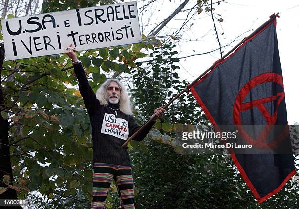 An anti-war activist holds a black anarchy flag and a poster that reads "U.S.A. And Israel, the real terrorist" during a protest against a possible...