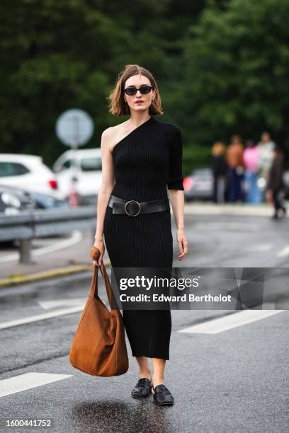 Guest wears black sunglasses, a black asymmetric shoulder / one long sleeve / long tube dress, a black shiny leather large belt, a camel suede large...