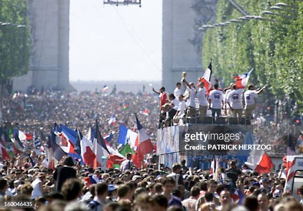 Players of the victorious French national soccer team hold the FIFA trophy during a parade on Champs Elysees avenue in Paris with the Arc de Triomphe...