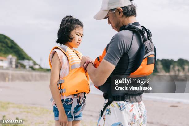 japanese father helping his daughter with life jacket - life jacket isolated stock pictures, royalty-free photos & images