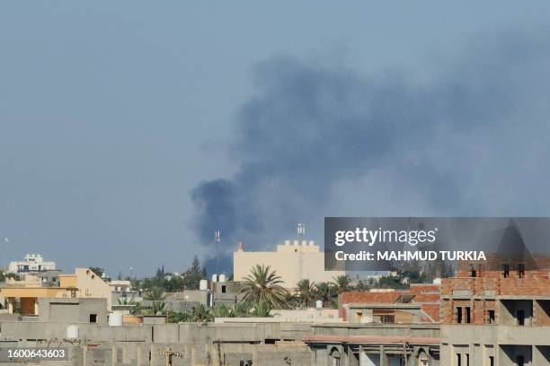 Smoke billows amid clashes between armed groups affiliated with Libya's Tripoli-based Government of National Unity in the Libyan capital on August...