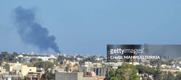 Smoke billows amid clashes between armed groups affiliated with Libya's Tripoli-based Government of National Unity in the Libyan capital on August...