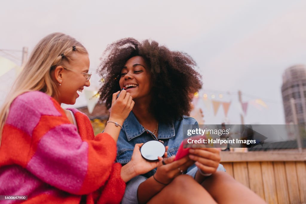 Young stylish girl zoomers doing make-up outdoors.