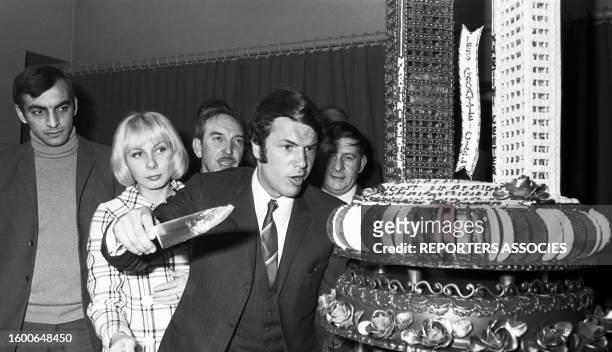 Salvatore Adamo coupant le gâteau sous les yeux de son épouse dans une soirée sponsorisée par 'Martini', en 1969.