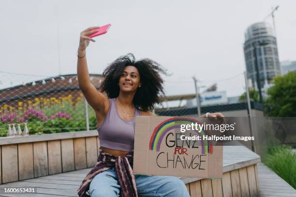 generation z activist with banner doing selfie, sharing her protest online. - climate change protest photos et images de collection