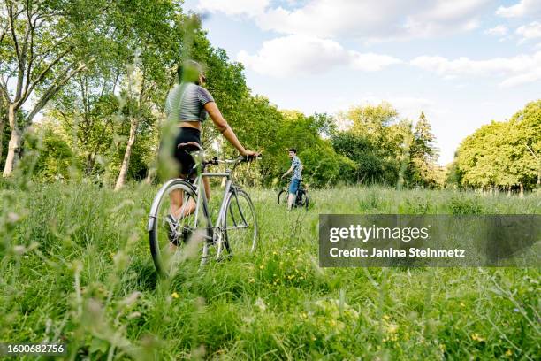 landscape formate of two young people with their bikes on a greenfield - bike flowers stock pictures, royalty-free photos & images