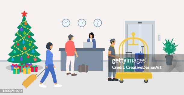 hotel reception with christmas tree and gift boxes. young man talking with receptionist and checking in to hotel. young woman pulling her luggage and bellboy with luggage trolley in lobby - conference hotel stock illustrations