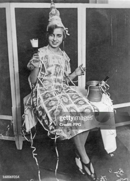 Woman at a masquerade in Amsterdam, Holland, wears a dress made out of 100 Mark notes, circa 1922. The Mark is almost worthless due to a period of...