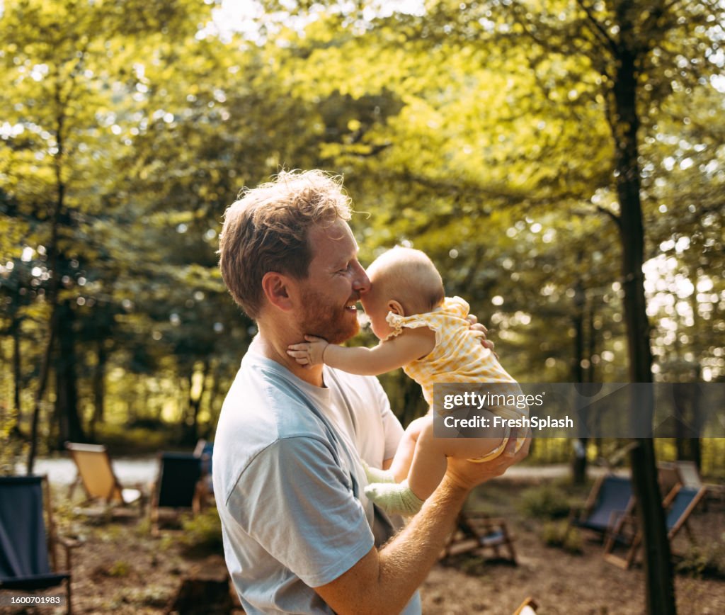 Portrait Of A Young Blonde Man Holding His Newborn Baby While