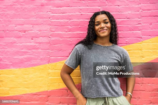 young generation z woman standing against brightly colored wall - dominikanischer abstammung stock-fotos und bilder