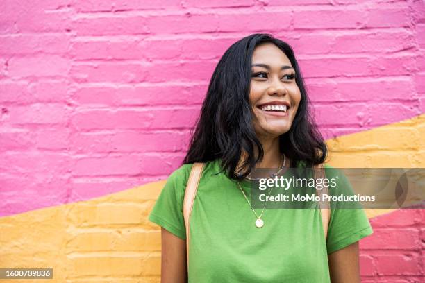 young generation z woman standing against brightly colored wall - levendige kleur stockfoto's en -beelden