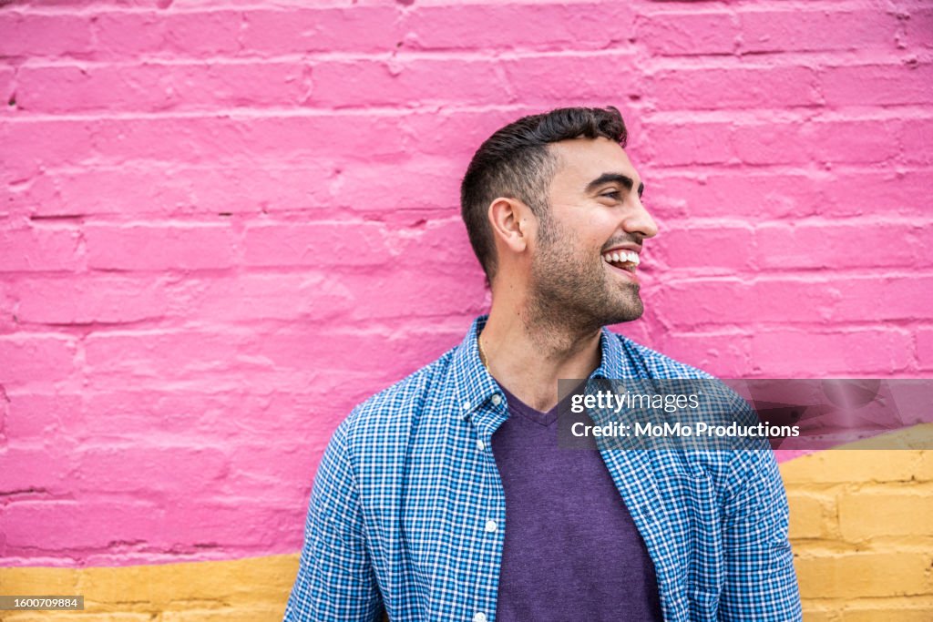 Portrait of young generation Z man standing against brightly colored wall