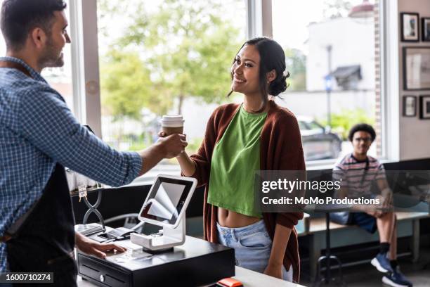 young woman buying a coffee with contactless electronic payment - receiving money stock pictures, royalty-free photos & images