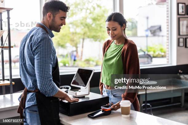 young woman buying a coffee with contactless electronic payment - tikken en betalen stockfoto's en -beelden