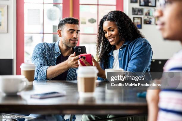 young couple using smartphones to transfer money - brand name mobile payment stockfoto's en -beelden