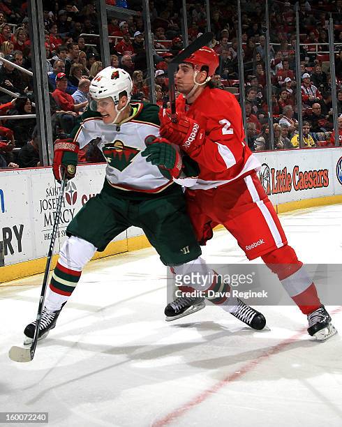 Brendan Smith of the Detroit Red Wings hits Justin Falk of the Minnesota Wild into the boards during a NHL game at Joe Louis Arena on January 25,...