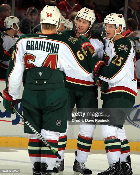 Mikael Granlund of the Minnesota Wild celebrates with teamates Tom Gilbert and Jonas Brodin after a goal during a NHL game against the Detroit Red...