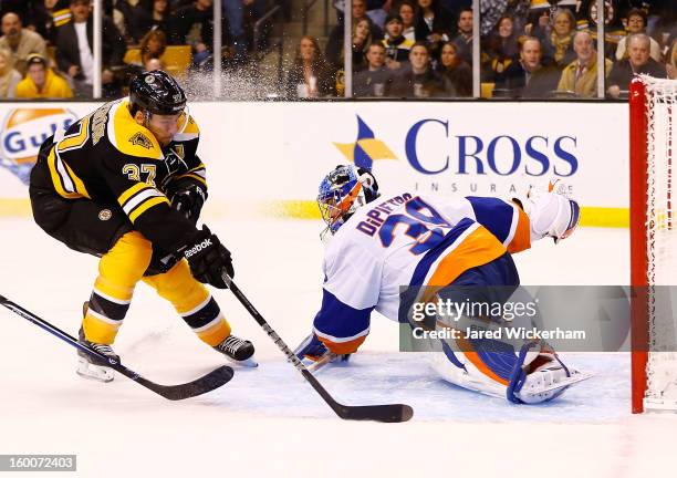 Patrice Bergeron of the Boston Bruins scores a goal around Rick DiPietro of the New York Islanders during the game on January 25, 2013 at TD Garden...
