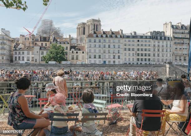 Tour boat sails past diners at a cafe on the banks of the River Seine in central Paris, France, on Monday, Aug. 14, 2023. July was officially Earth's...